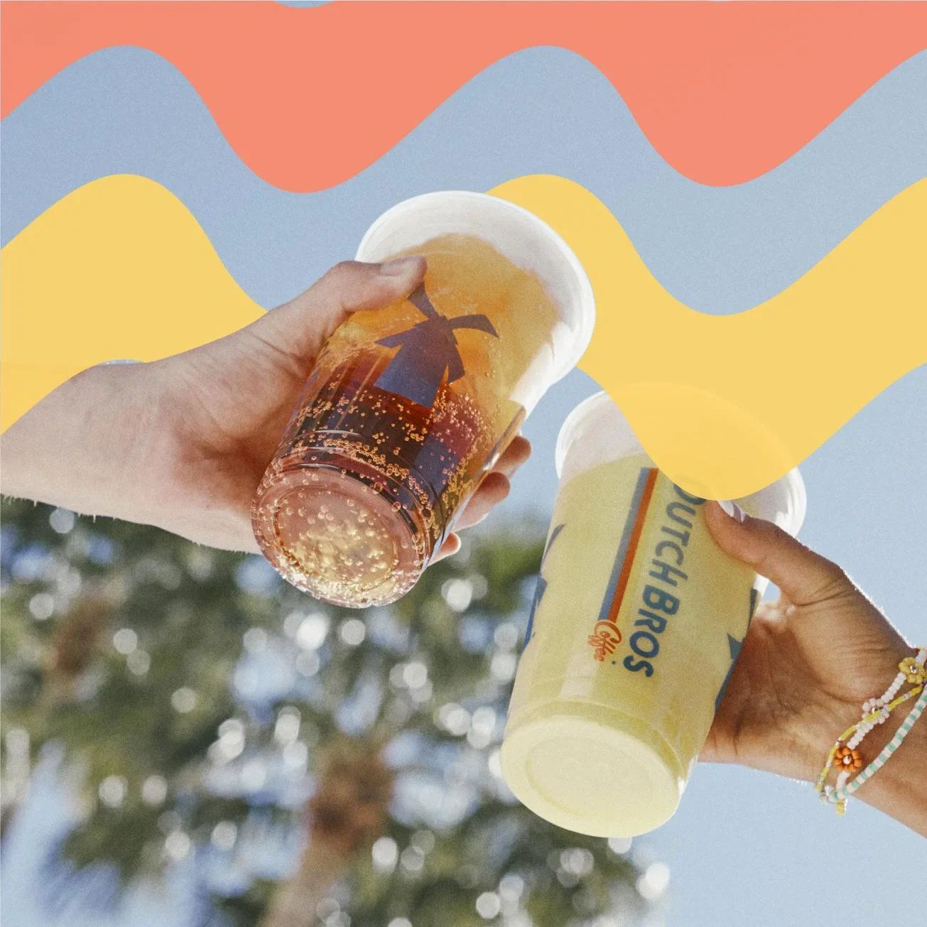 Two hands holding beverages in plastic cups against colorful wavy background of coral, blue, and yellow.