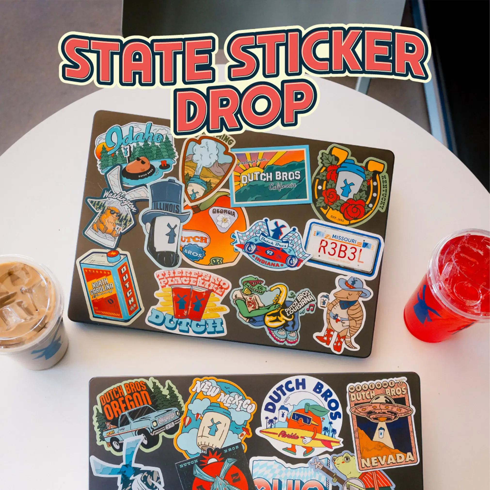 Two laptops covered in colorful Dutch Bros state-themed stickers, with iced drinks nearby and "State Sticker Drop" text above.