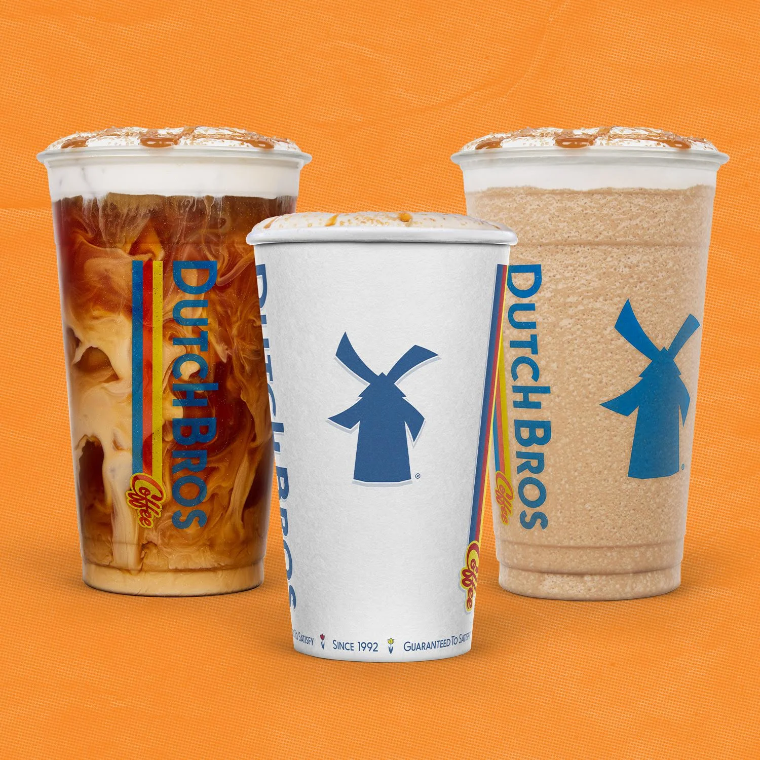Three Dutch Bros coffee drinks in clear cups with blue windmill logos on orange background - iced coffee and blended beverages.