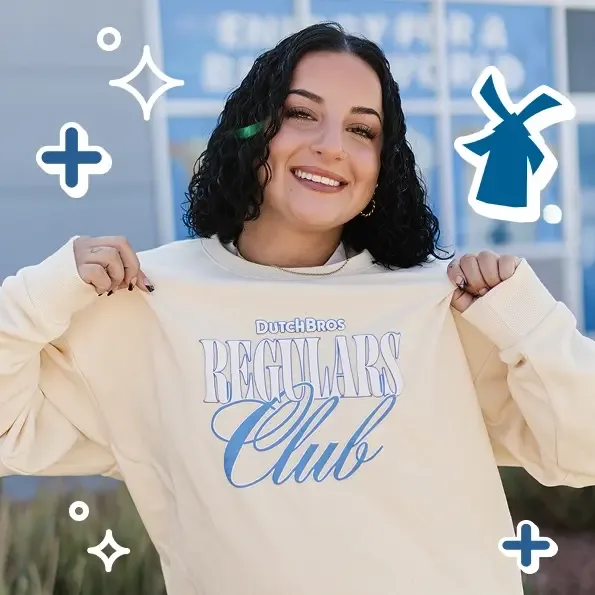 Person with curly hair smiling in cream "Dutch Bros Regulars Club" sweatshirt, with blue decorative icons around the image.