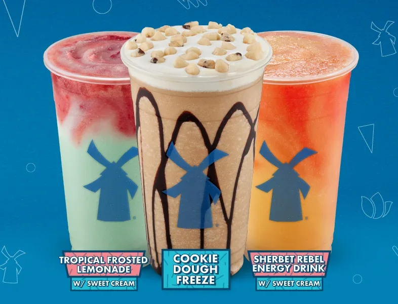 Three Dutch Bros drinks: Tropical Frosted Lemonade, Cookie Dough Freeze with toppings, and Sherbet Rebel Energy Drink on blue background.