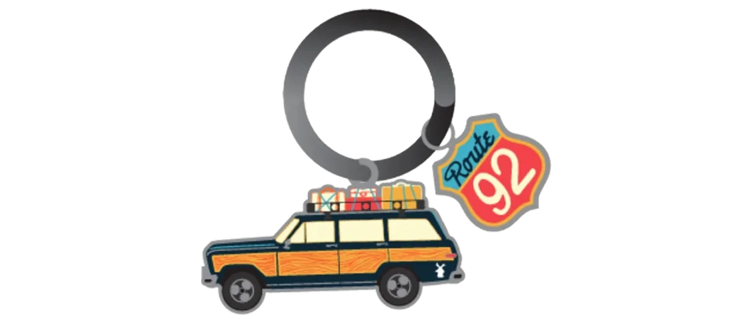 A keychain featuring a retro station wagon with roof luggage and a colorful Route 92 road sign charm on a metal ring.