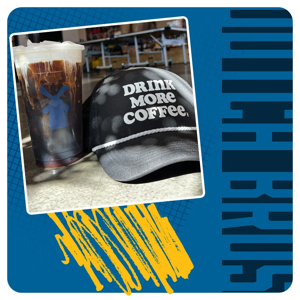 Iced coffee drink in clear cup next to black cap with "DRINK MORE COFFEE" text against blue background with yellow accent.