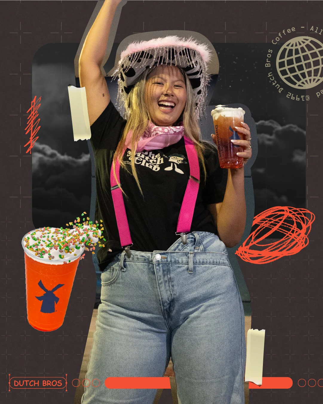 Person wearing decorative hat and pink suspenders joyfully holding Dutch Bros coffee drink against dark background.