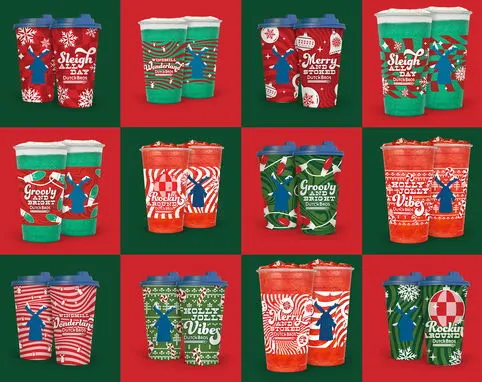 Collection of festive holiday coffee cups in red and green designs featuring seasonal patterns and Christmas messages.
