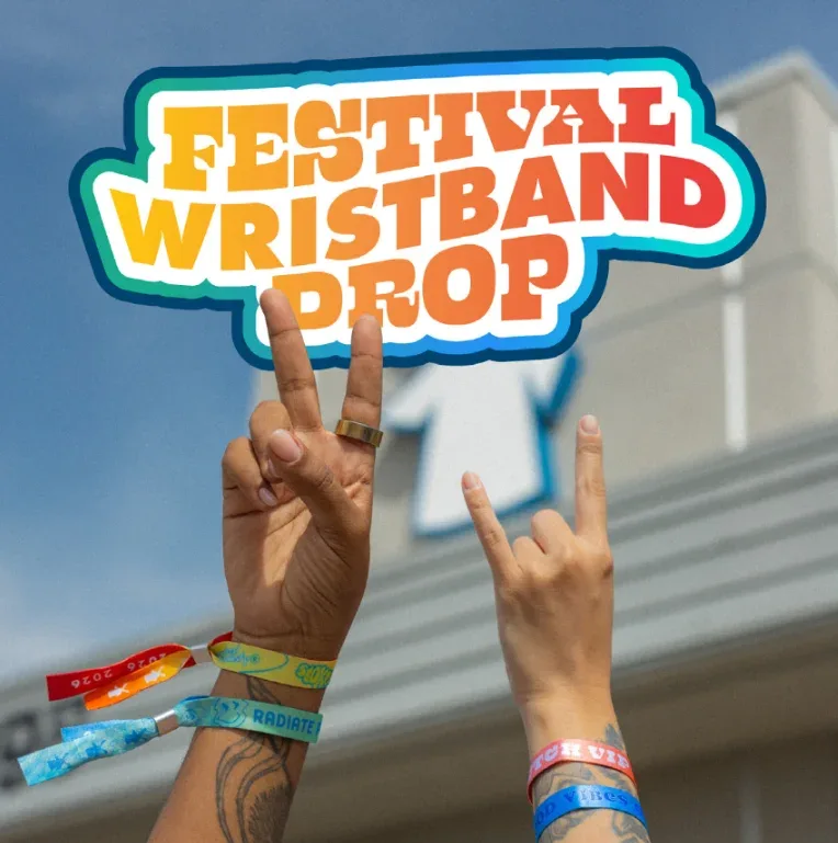 Hands making peace signs wearing colorful festival wristbands against blue sky, with "FESTIVAL WRISTBAND DROP" text overlay.