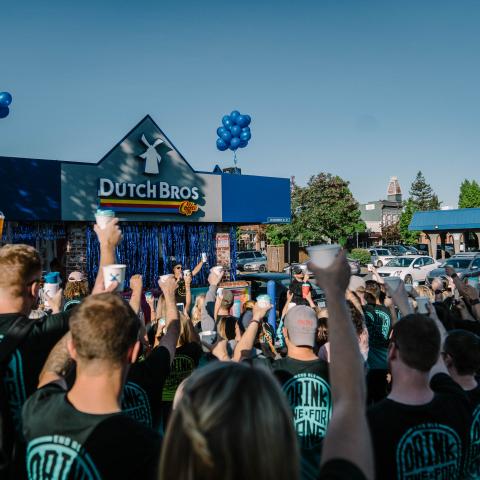 A large group of people put their cups up in the air in solidarity 
