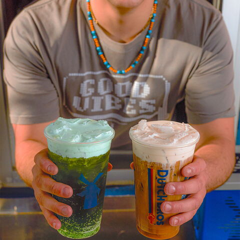 A Dutch Bros broista hands two Rebel energy drinks through the drive through window