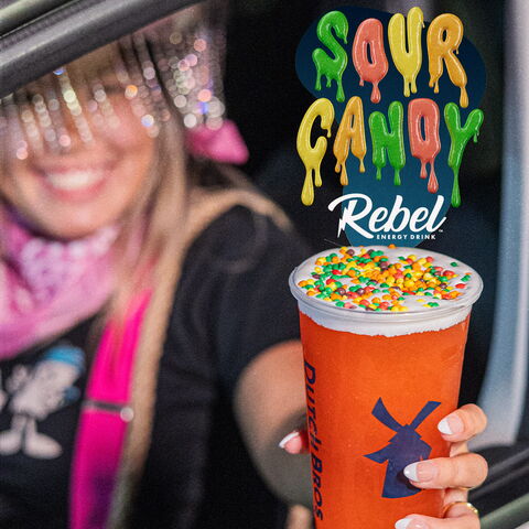 a girl in a car handing a sour candy rebel out of the window