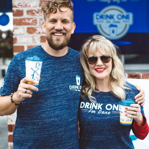 Two people smile and embrace outside of a dutch Bros location