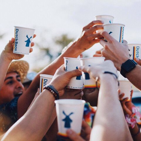 a group of Dutch Bros fans raise their coffee cups to cheers