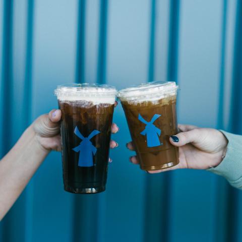 Two people doing a cheers with their large iced Dutch Bros drinks