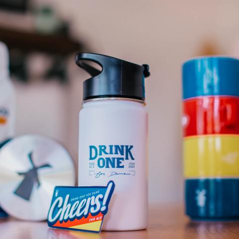 A white insulated bottle that says Drink One For Dane is shown on a desk