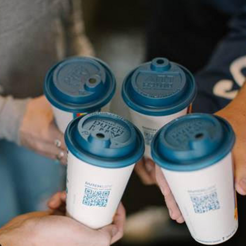 A group of coffee cups held in a cheers by a group of people
